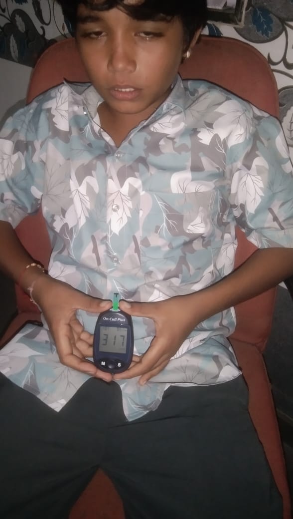 Boy sitting on a chair holding a glucometer showing 317